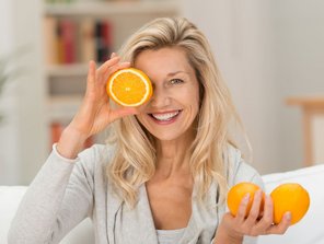 Eine Frau hält sich eine durchgeschnittene Orange vor das Auge